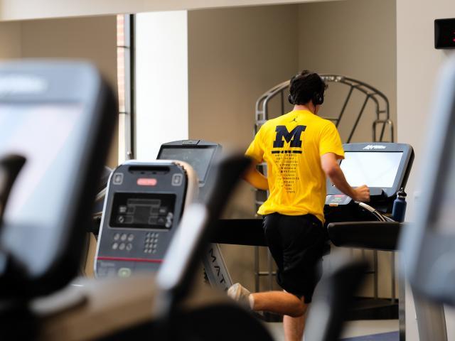 A man running on a treadmill with a Michigan shirt