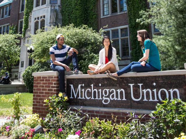 Students sitting on the Michigan Union sign